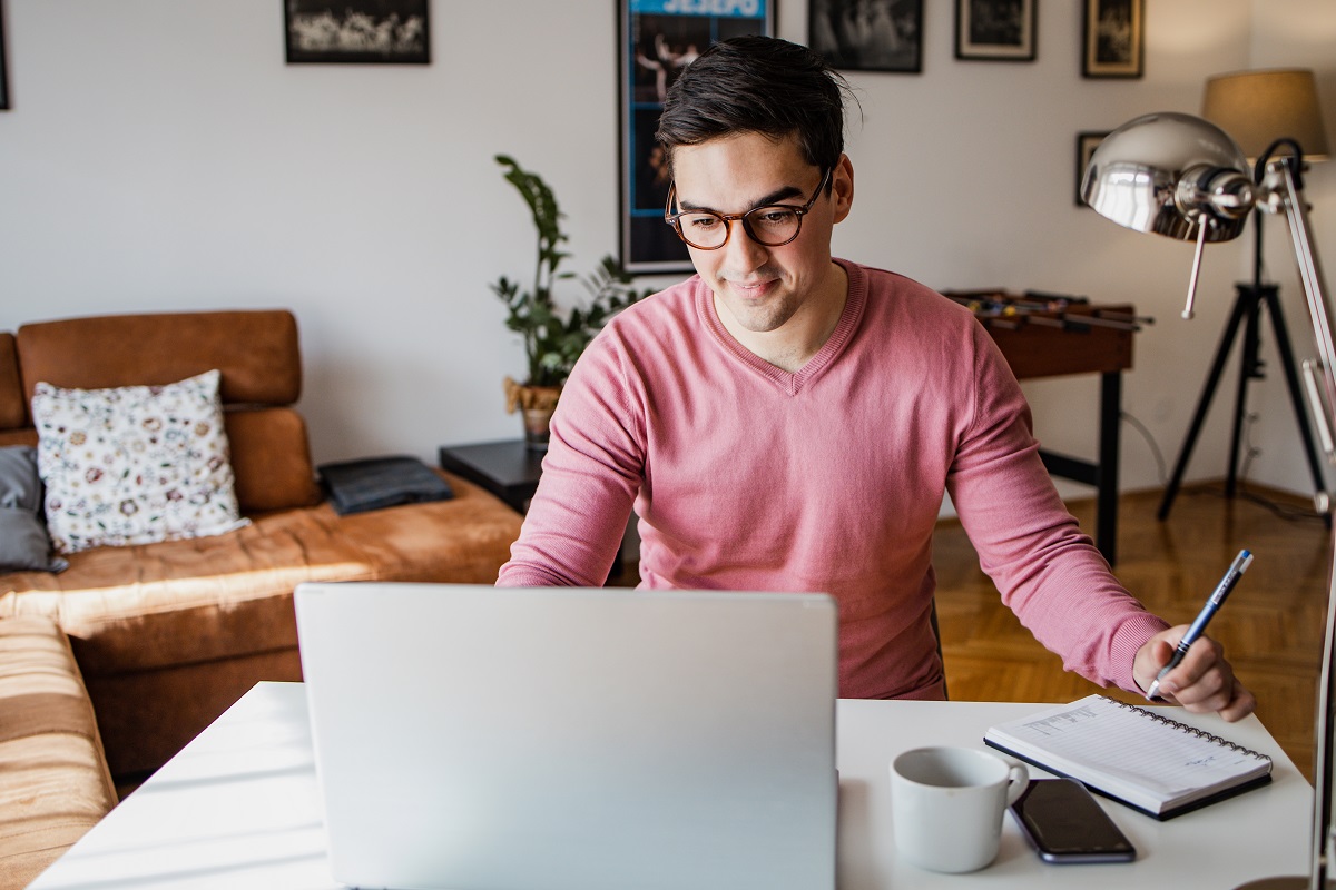 Picture of a young man with dark hair. He's seated at a desk and working on a laptop computer. He is taking proactive steps to safeguard his accounts from fraud.